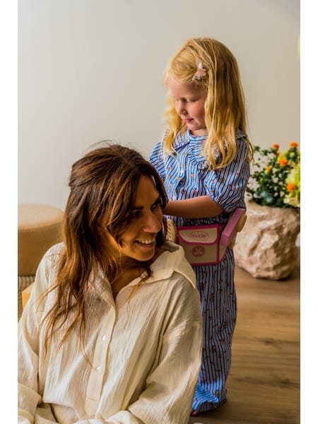 To personer i afslappet tøj ser på en lille lyserød legetøjsæske med tilbehør.